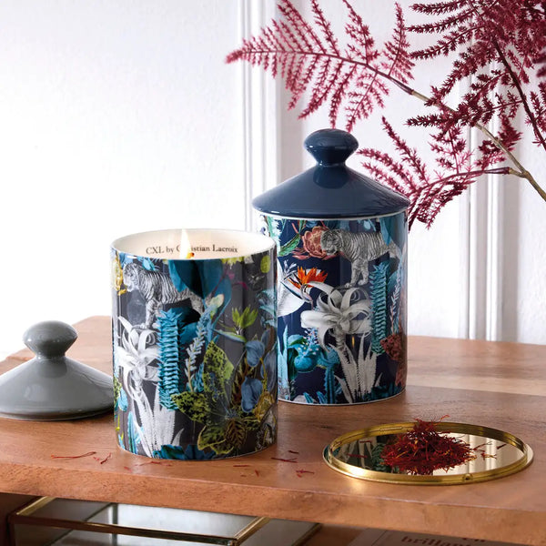 Pot en céramique bleu foncé pour bougie avec des illustrations élaborées de faune et de botanique en tons blanc, vert et or.